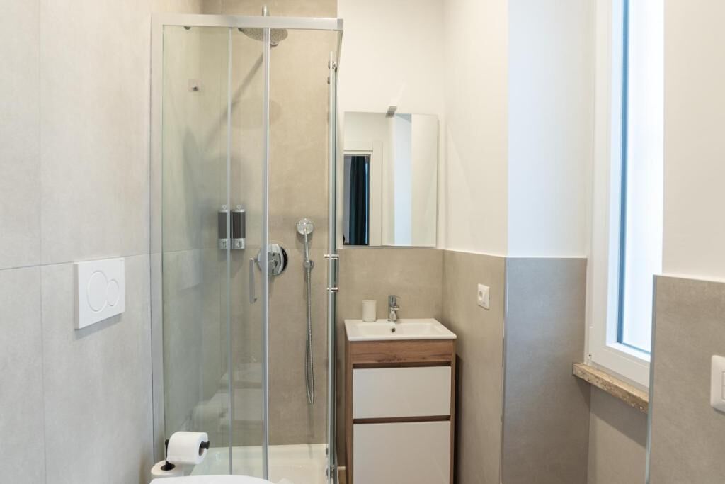 Une salle de bain moderne avec une douche à parois de verre, un meuble-lavabo en bois et un miroir.