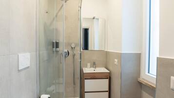 Une salle de bain moderne avec une douche à parois de verre, un meuble-lavabo en bois et un miroir.