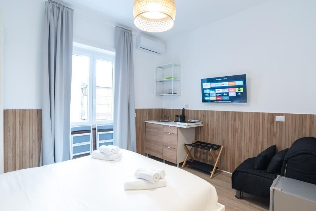 Une chambre d’hôtel avec un lit, un bureau, une chaise, une télévision et un balcon.
