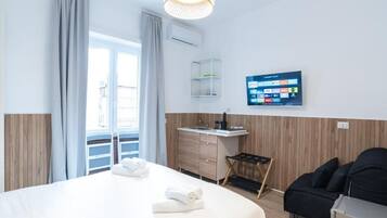 Une chambre d’hôtel avec un lit, un bureau, une chaise, une télévision et un balcon.