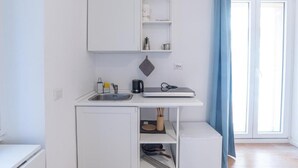 A compact kitchenette with a sink, a coffee maker, and a small refrigerator.