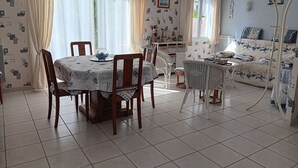 Un comedor con una mesa dispuesta para cuatro personas, sillas alrededor y un sofá al fondo.