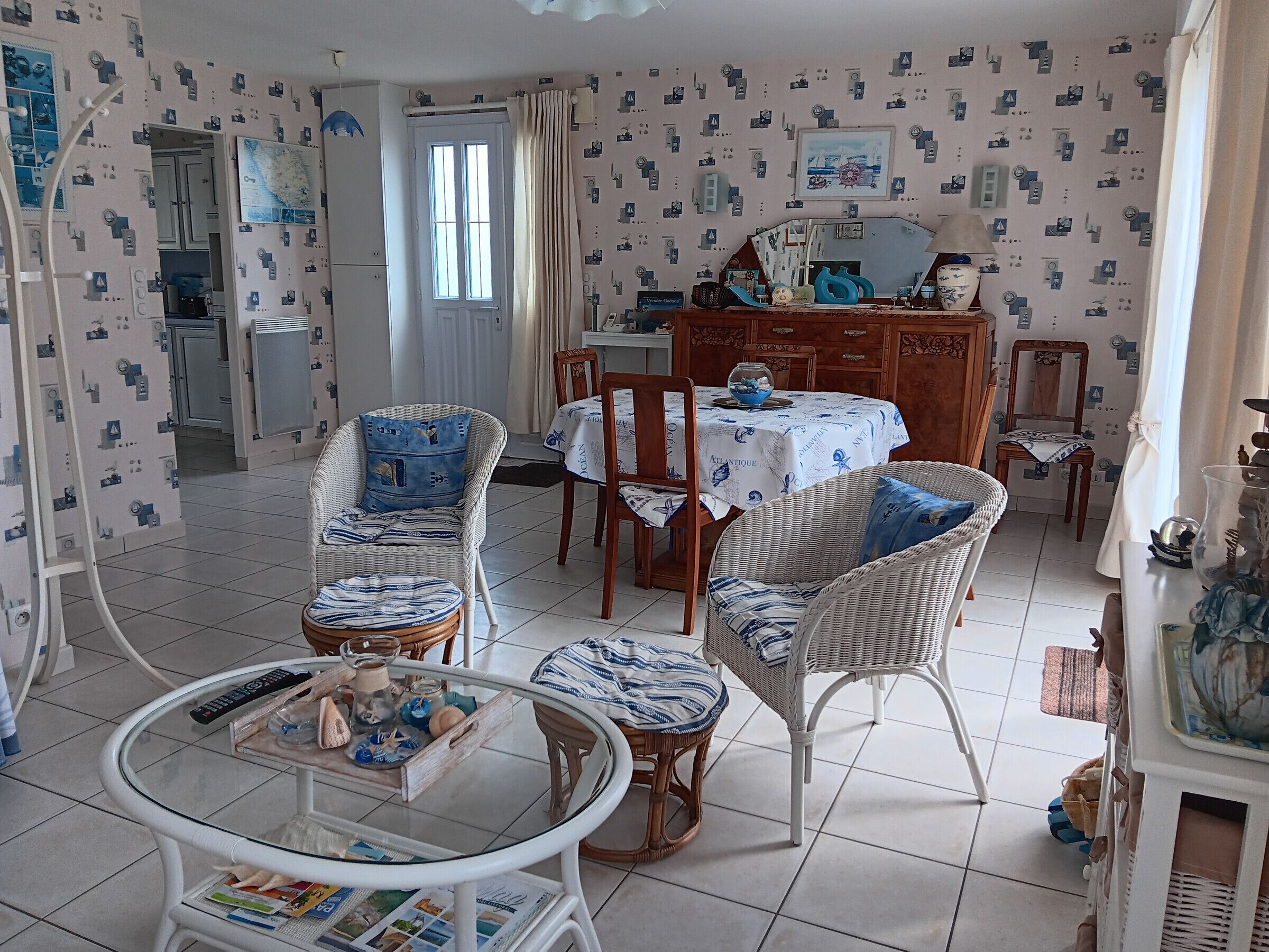 Un coin repas avec des chaises en osier, une table ronde en verre et un buffet en bois.