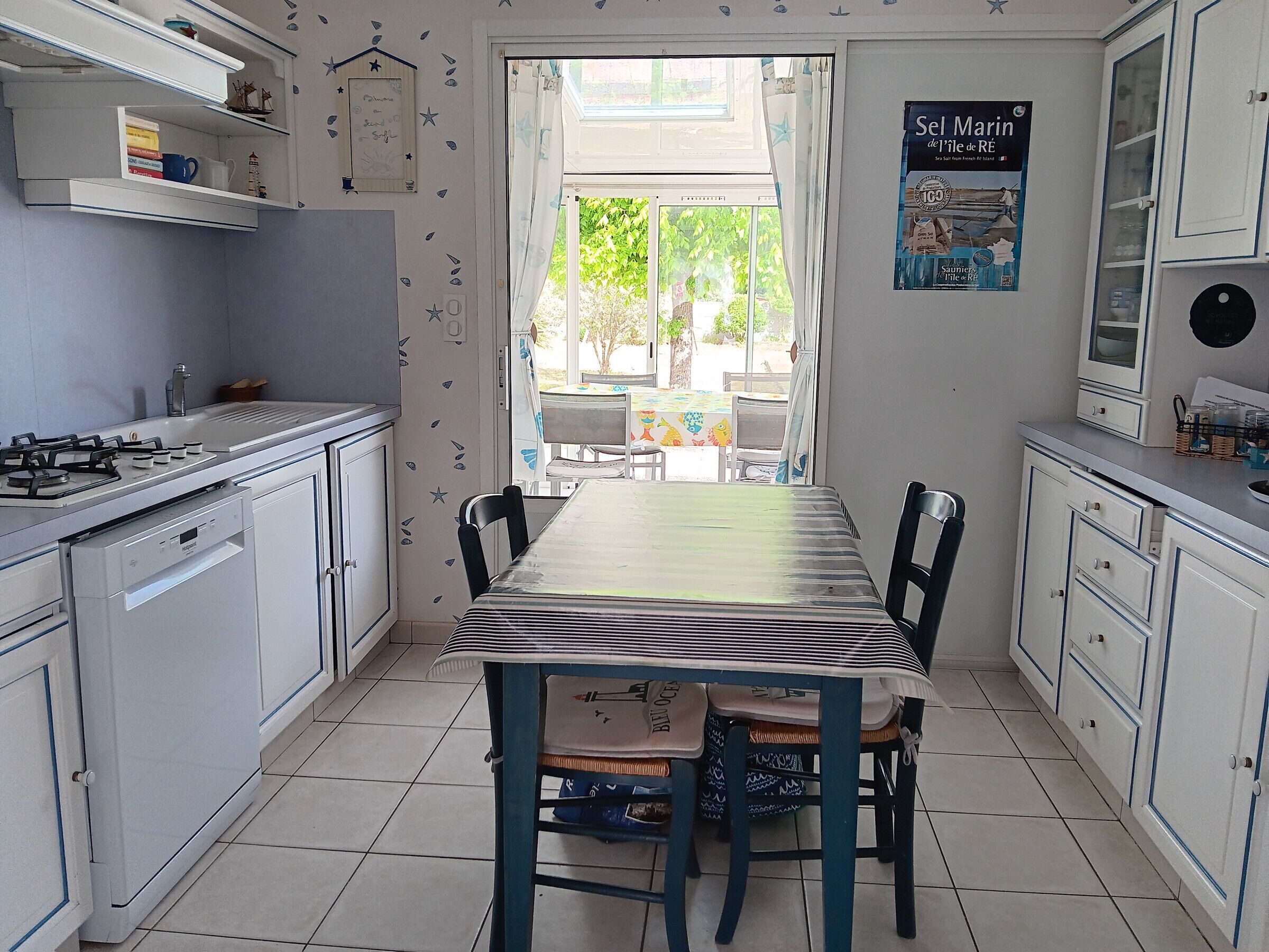 A kitchen with white cabinets, a gas stove, a dining table with chairs, and a view through a window.