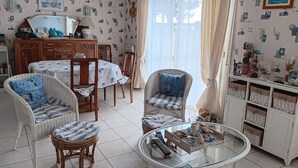 Una sala de estar con muebles de mimbre, una mesa de centro de vidrio y un comedor con una mesa y sillas.