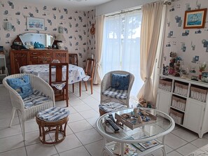 Ein Wohnzimmer mit Rattanmöbeln, einem Glastisch und einem Essbereich mit Tisch und Stühlen.