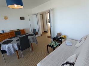 Ein Hotelzimmer mit einem Bett, einem Esstisch mit Stühlen, einem kleinen Tisch mit Lampe und einem Spiegel an der Wand.