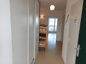 Ein schmaler Flur mit einem Etagenbett, einer Tür und einem Fenster.