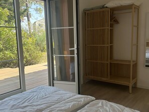 Ein Schlafzimmer mit einer großen Schiebetür, einem Holzschrank und einem Bett mit weißer Bettwäsche.