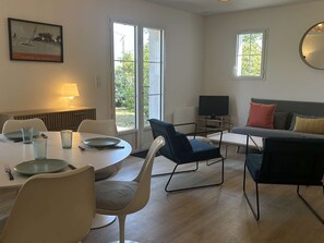 Ein modernes Wohnzimmer mit Essbereich, einer Couch, einem Fernseher und einem Bild an der Wand.