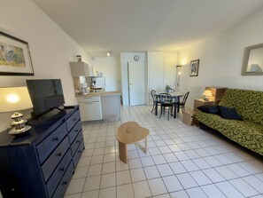 Ein kompakter Wohnbereich mit Küchenzeile, Essbereich, einer Couch und einem Fernseher.