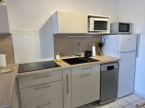 Eine kleine Küche mit Spüle, Mikrowelle, Kühlschrank und Geschirrspüler.