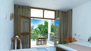 Quarto com cama, escrivaninha e cadeira. Possui janela com cortinas e varanda com mesa e cadeiras.