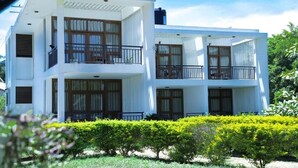 Um edifício moderno de dois andares com varandas, grandes janelas e um jardim bem cuidado.