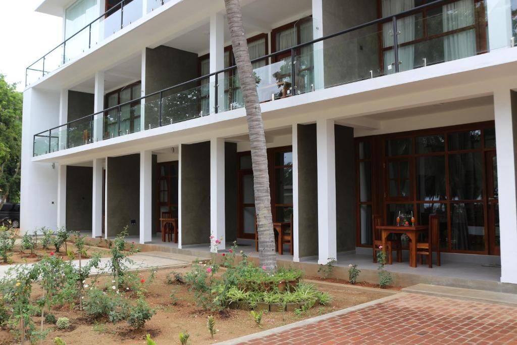 A multi-story building with balconies, a garden area with plants, and a brick pathway.