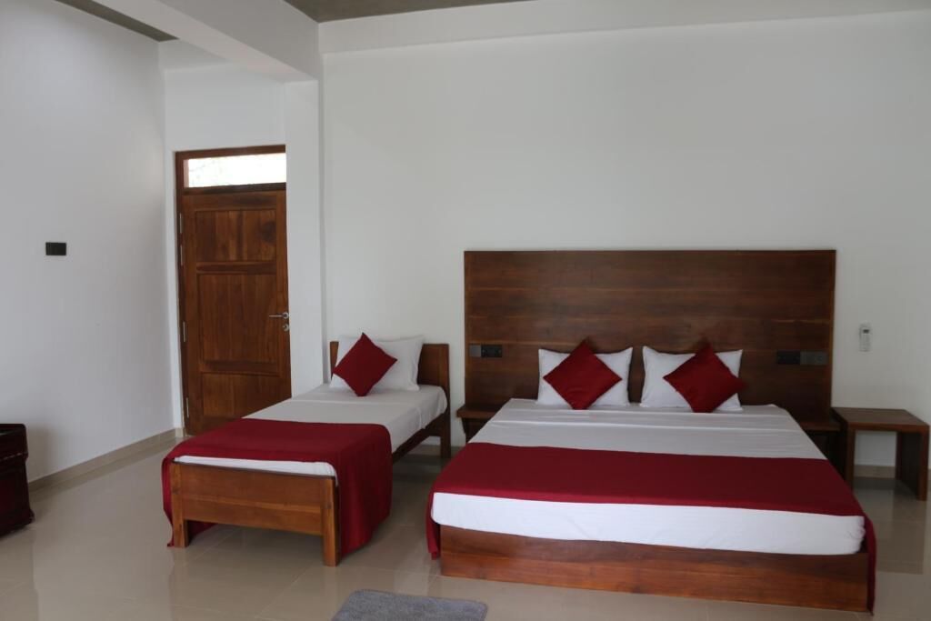 Ein Hotelzimmer mit zwei Betten, Holz-Kopfteilen und einer roten Bettdecke.
