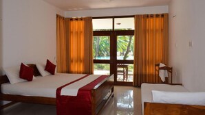 Quarto de hotel com cama, poltrona, mesa e vista para palmeiras pela janela.