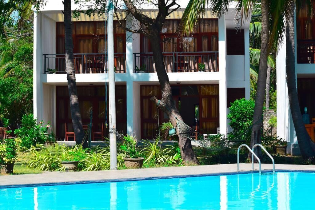 Un hotel con piscina, varios balcones y abundante vegetación.
