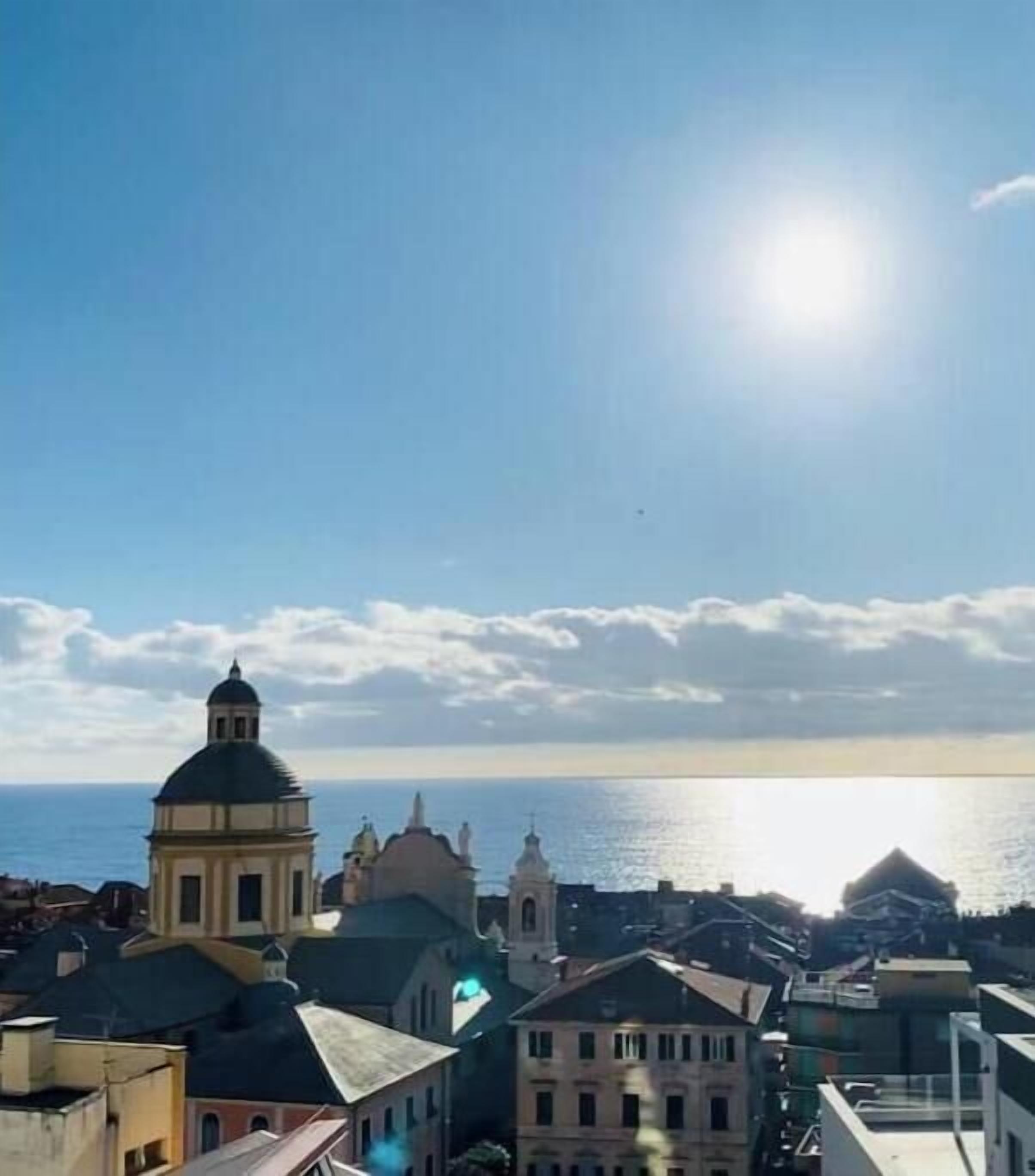 Paisagem costeira urbana com uma cúpula de igreja em destaque, um corpo de água e um céu claro.
