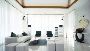 A modern living room with a white sofa, green chairs, a coffee table, and a decorative plate on a console table. - Lore Resorts and conventions (Maheshwaram)