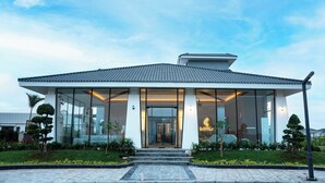 A modern building with a tiled roof, large glass windows, and a well-maintained garden. - Lore Resorts and conventions (Maheshwaram)