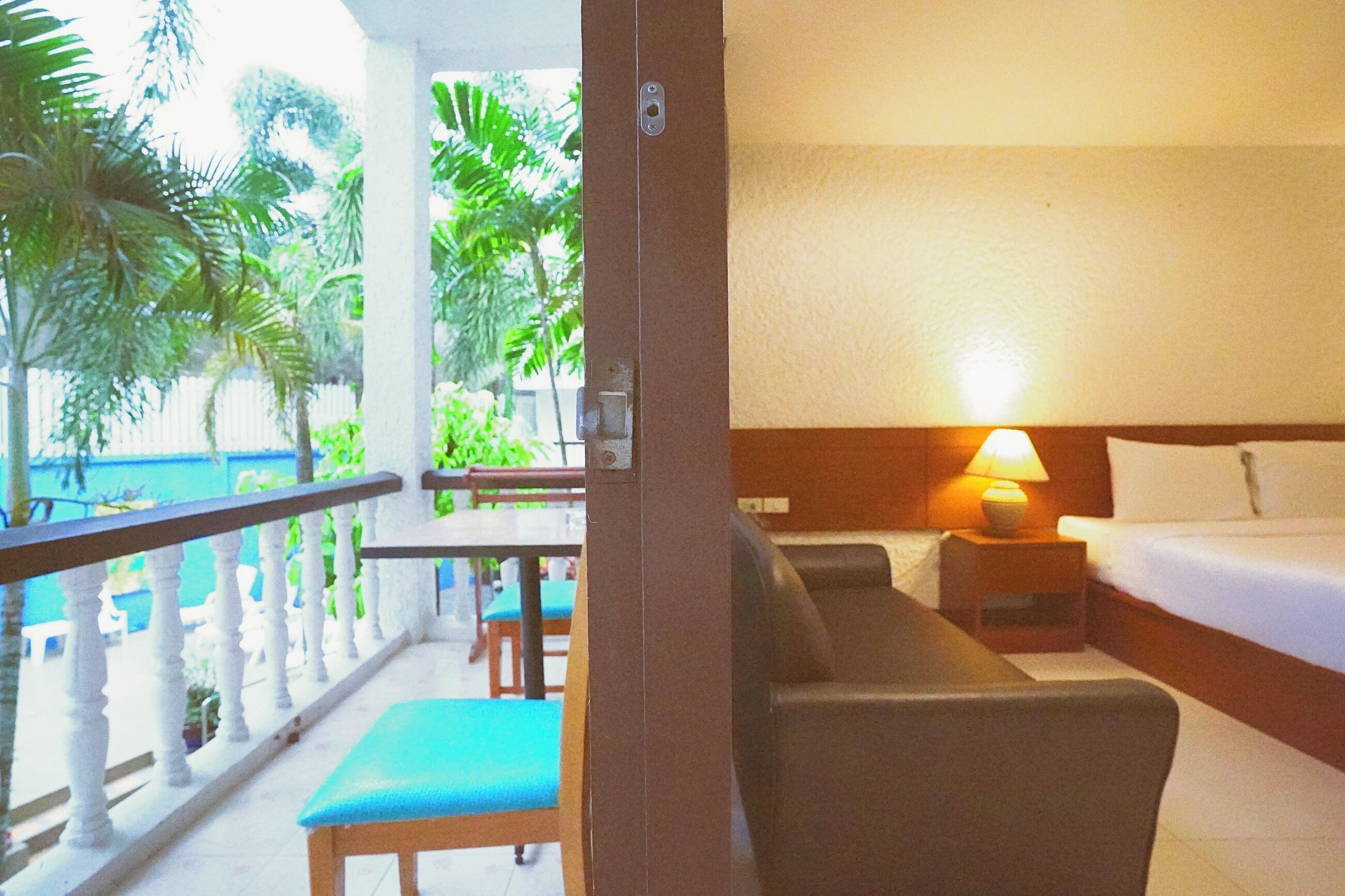 A hotel room with a balcony, a bed, a nightstand with a lamp, and a view of the ocean.