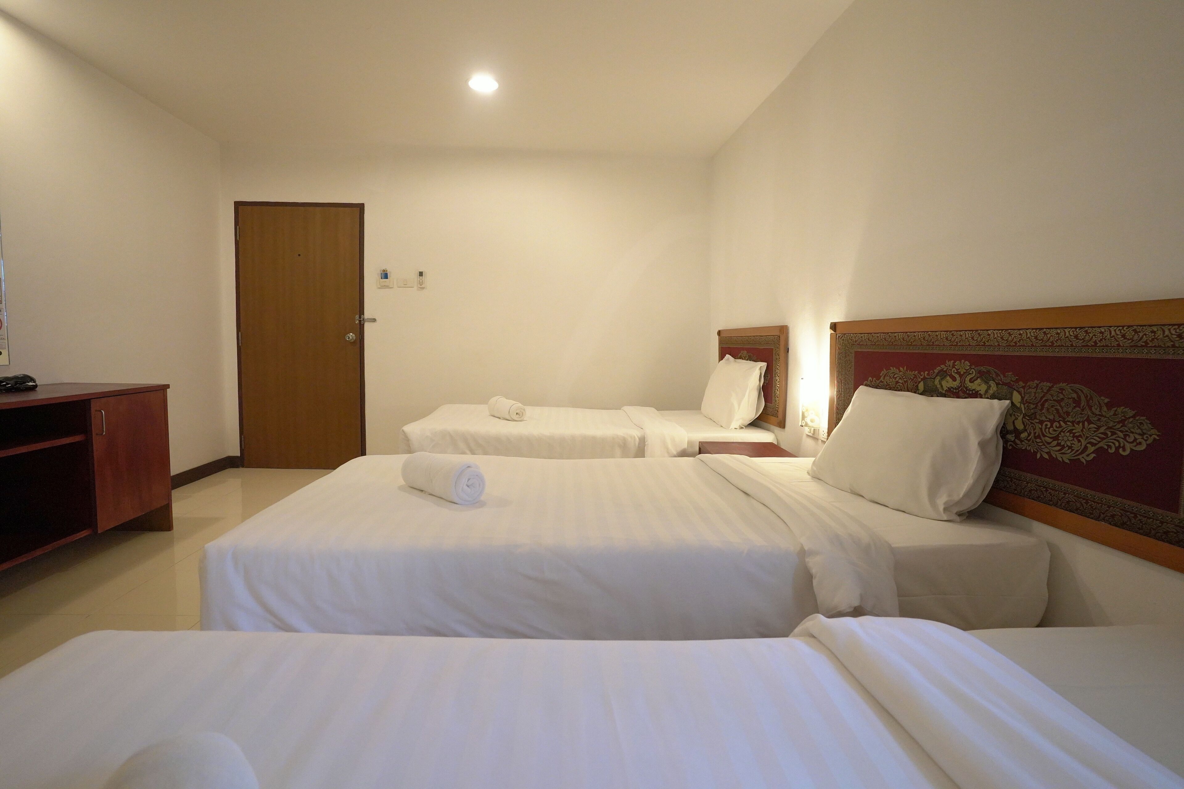 Habitación de hotel con dos camas, cabecera de madera, un escritorio pequeño y una puerta.