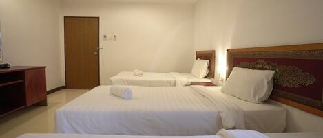 Habitación de hotel con dos camas, cabecera de madera, un escritorio pequeño y una puerta.