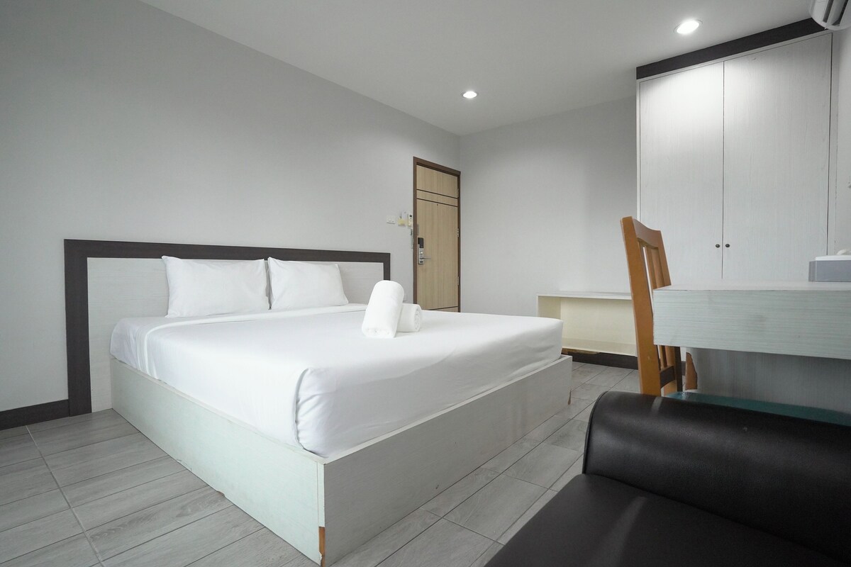 A hotel room with a bed, a desk, a chair, and a wardrobe.