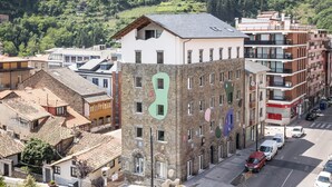 Un edificio de varios pisos con una mezcla de arquitectura tradicional y moderna, destacando una gran letra verde en la fachada.