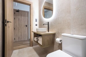 Une salle de bain moderne avec une porte en bois, un lavabo intégré, des toilettes et un miroir.