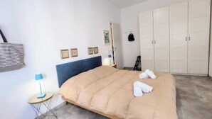 Ein Schlafzimmer mit einem Bett, einem Kleiderschrank, einer Lampe und einem kleinen Tisch.