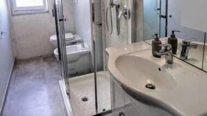 Ein modernes Badezimmer mit einer gläsernen Dusche, einem großzügigen Waschbecken und einem Spiegel.