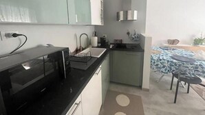 Eine moderne Küche mit schwarzer Arbeitsplatte, einem Spülbecken und einer kleinen Essecke mit Tisch und Stühlen.