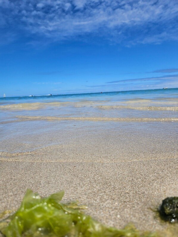 A beach with clear water and a distant boat.