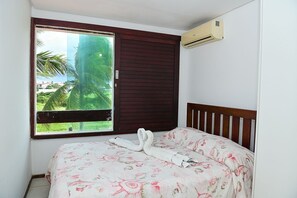 Una habitación con cama, ventana y vistas a zonas verdes, además de un equipo de aire acondicionado.