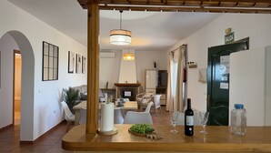 A modern kitchen with a wooden counter, a hanging light fixture, and a dining area in the background. - Cortijo del Verdial by At Home Costa del Sol (Torrox)