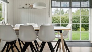 A dining area with a white table, black chairs, and a large window with a view of greenery.