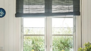 A room with a window, a chair, a potted plant, and a cabinet.