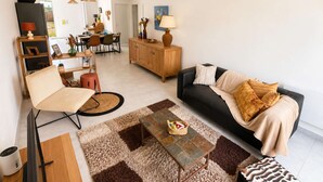Een moderne woonkamer met een bank, fauteuil, salontafel en eethoek.