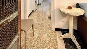 Um corredor com papel de parede estampado, uma mesinha e uma cadeira.