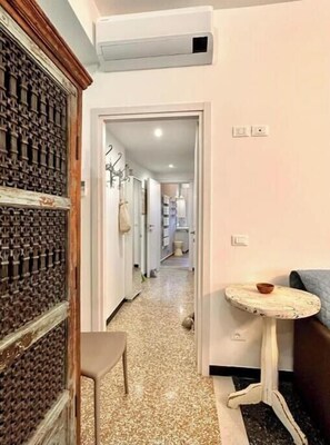 A hallway with a patterned wall, a small table, and a chair. - Hostdomus - Tiffany House (Finale Ligure)