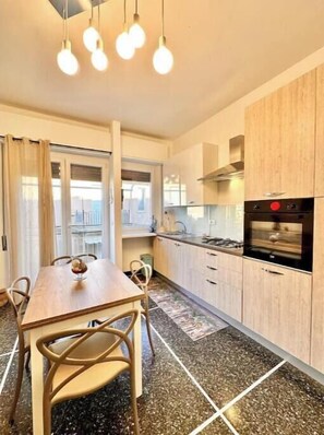 A modern kitchen with a dining table, chairs, and a stove. - Hostdomus - Tiffany House (Finale Ligure)