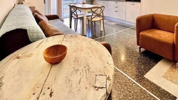 Uma sala de estar moderna com uma mesa de jantar, sofá e televisão na parede.