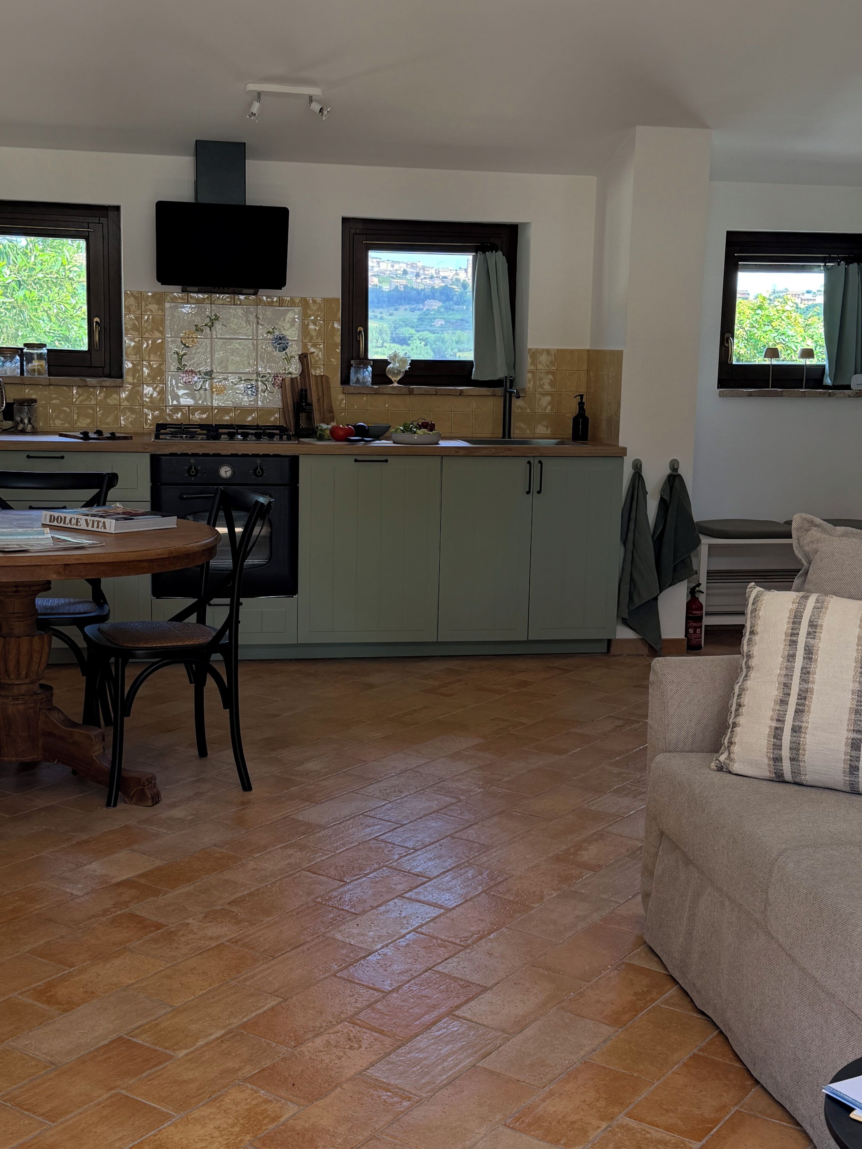 A kitchen with a dining table, chairs, and a sofa.
