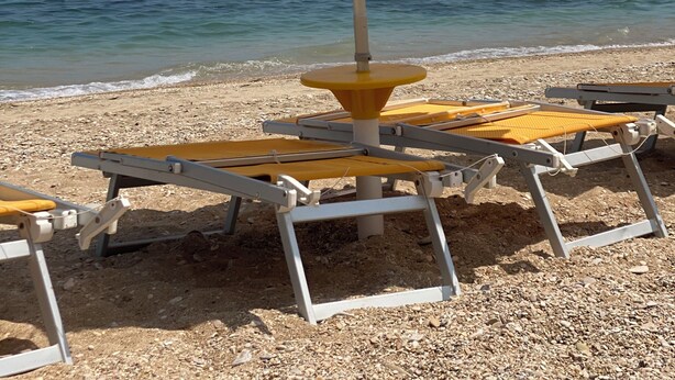 Ein Strand mit gestreiften Sonnenschirmen und Liegestühlen.