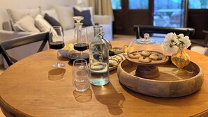 Ein runder Holztisch mit einer Flasche, Gläsern und einer Schale Kekse.