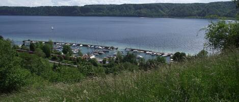 A marina with boats docked, surrounded by greenery and a lake.