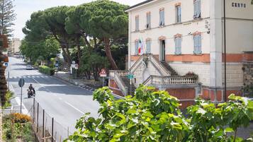 Straßenansicht mit einem Gebäude mit der Aufschrift 'CERVO', einer Fußgängerzone und einem Motorradfahrer.