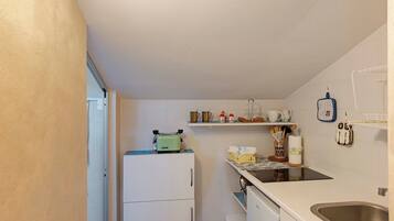 Een koelkast, een oven, een kookplaat, kookgerei, borden en bestek